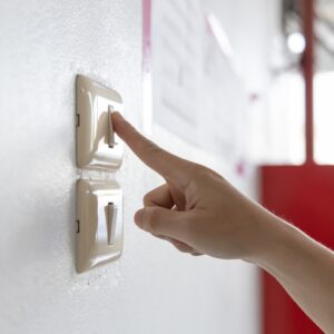 A student flipping a light switch in a classroom