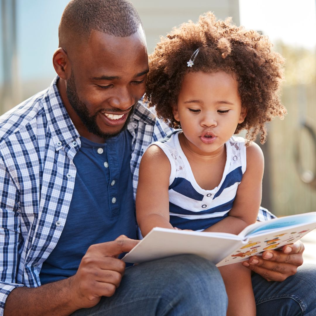 img of a man reading to his daughter